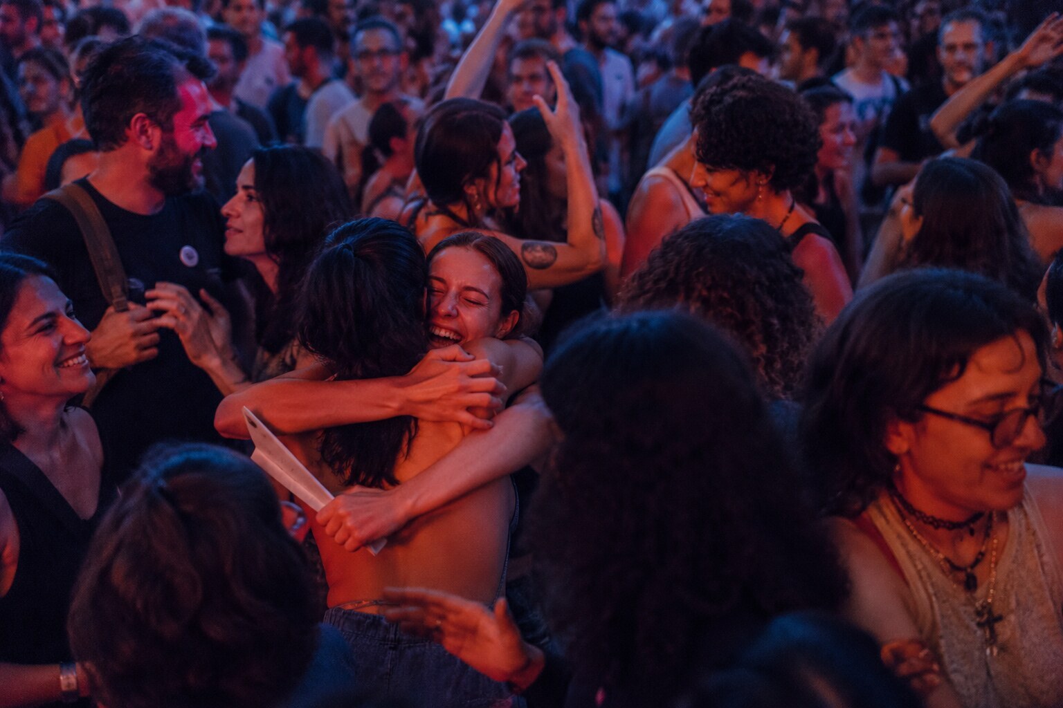 Personas celebrando juntas bajo luces azules y rosadas